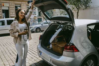 Mature woman standing by car trunk at roadside