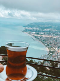 Glass of coffee in city against sky