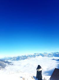 Woman on snowcapped mountain against clear blue sky