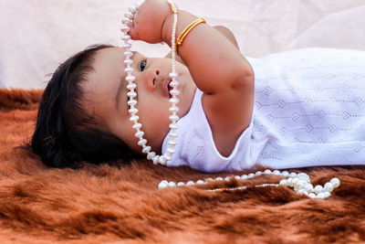 Cute girl with necklaces lying down on bed