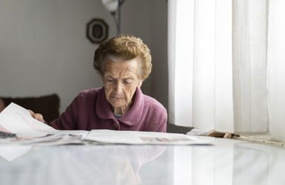 Senior woman reading newspaper at dining table