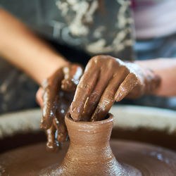 Midsection of woman making pot in workshop