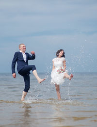 Young couple dancing in sea against sky