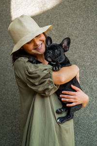 Mid section of woman with dog wearing hat