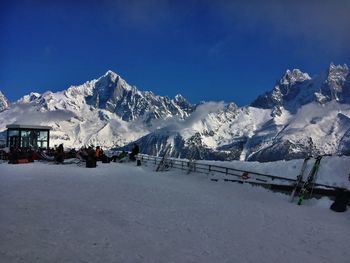 Scenic view of snow covered mountains against blue sky