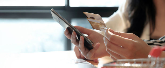 Midsection of woman holding smart phone on table