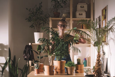 Woman watering potted plants using spray bottle at home