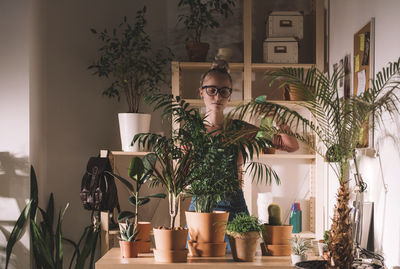 Portrait of young man by potted plant at home