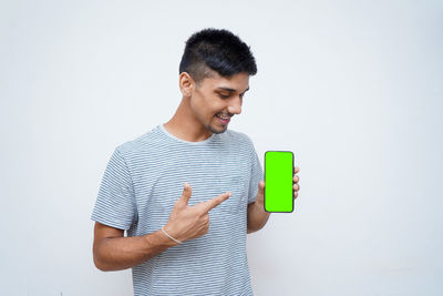 Young man looking away while standing against white background