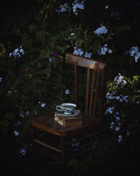 High angle view of tea cup and book on empty chair at yard