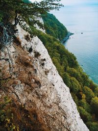 Scenic view of sea by mountain against sky