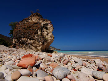 Rocks on beach against clear blue sky