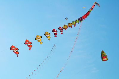 Low angle view of flags hanging against clear blue sky