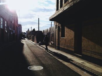 Empty road in city against cloudy sky