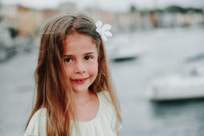 Portrait of smiling girl standing against river 