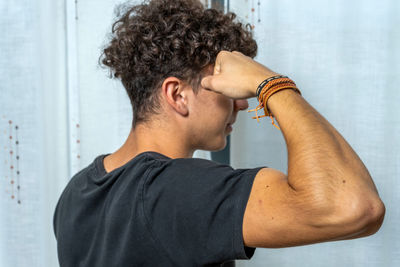 Rear view of young man flexing muscle at home