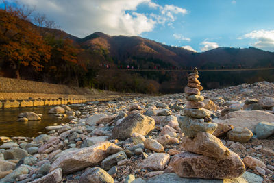 Rocks on shore by lake against sky