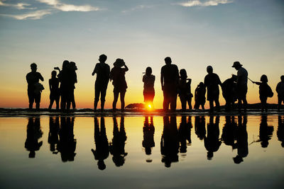 Silhouette people standing against sky during sunset