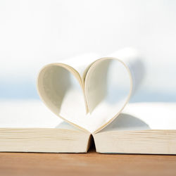 Close-up of paper forming heart shape on book