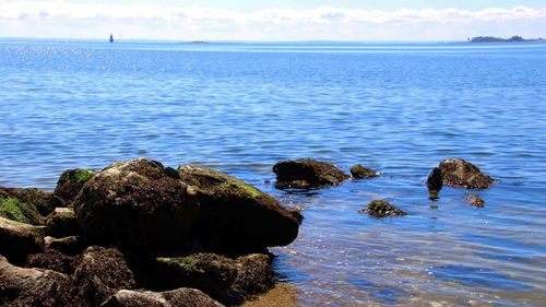 Rocks on sea shore against sky