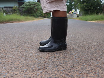 Low section of person in gum boots standing on road