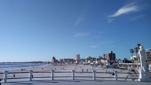 People on beach against clear blue sky