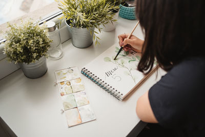 Crop from above view of unrecognizable woman drawing picture with watercolors at home in paris