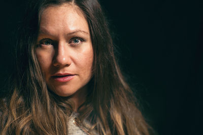 Close-up portrait of smiling woman against black background