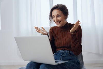 Young woman using laptop while sitting on sofa at home