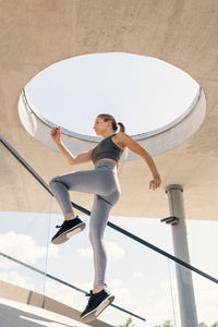 Faster with music. low angle view of young woman jumping against sky.