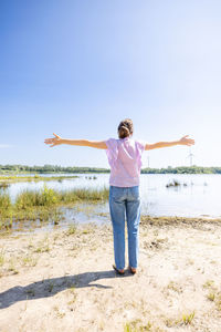 Rear view of woman standing at beach