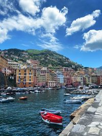 Sailboats moored on harbor by buildings in city against sky