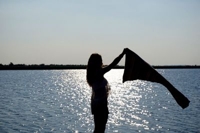 Rear view of woman standing in sea against clear sky