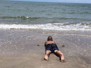 Full length of shirtless man on sea shore