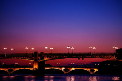 Bridge over river against sky at dusk