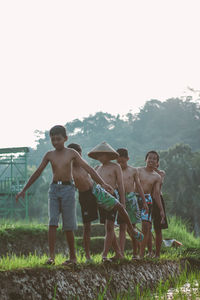 Full length of shirtless boy on land against clear sky