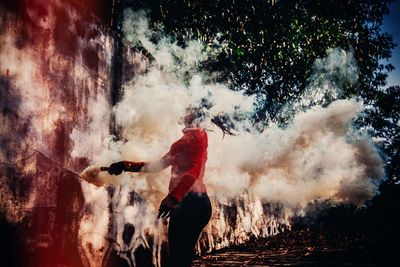 Woman holding distress flare against trees