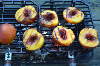 Peach halves grilling on top of a small tabletop hibachi grill on picnic table outdoors