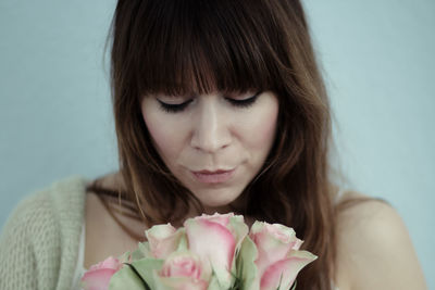 Close-up of woman with roses against blue background