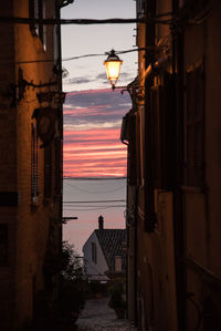 Low angle view of street light amidst buildings against sky