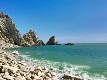 Scenic view of beach against clear blue sky