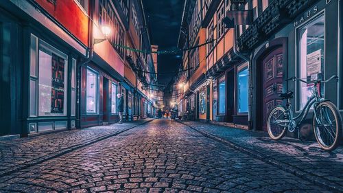 Empty street in illuminated city at night