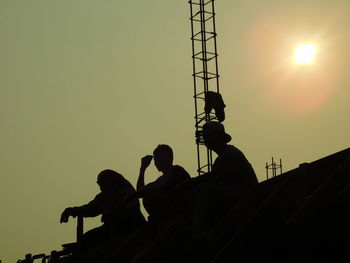 Low angle view of men working against sky during sunset