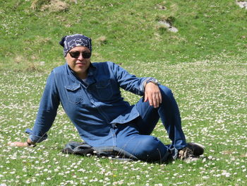 Portrait of mid adult man wearing sunglasses sitting on grassy field at park