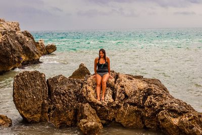 Woman siting on rock against sea