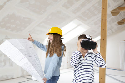 Girl holding plan while brother using vr headset