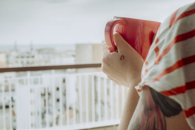 Close-up of woman holding red mug on balcony