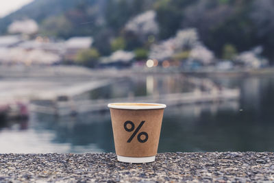 Close-up of coffee cup on rock by river