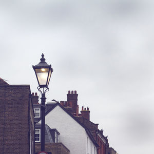 Low angle view of illuminated street light against building