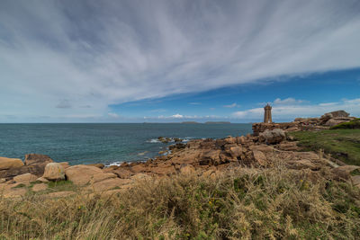 Rocks on shore by sea against sky
